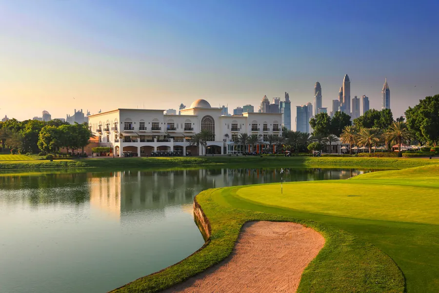 Clubhouse beside a lake and green with a city skyline behind